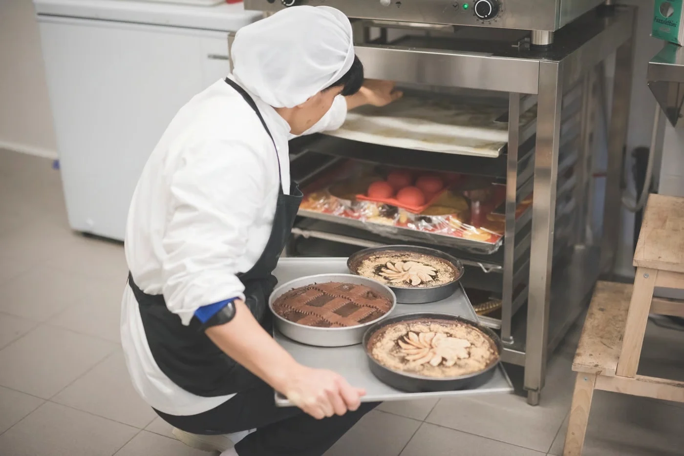 Emily Parker Baking Tarts in Oven | CookEaseNow Chef Emily Parker carefully placing a tray of freshly baked tarts into a professional oven at CookEaseNow.